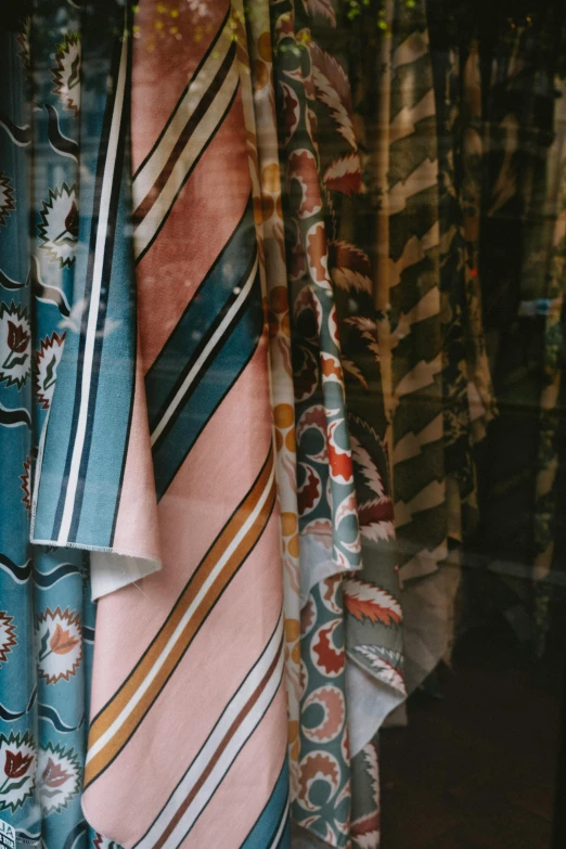 several different tie laying on a rail in front of a window