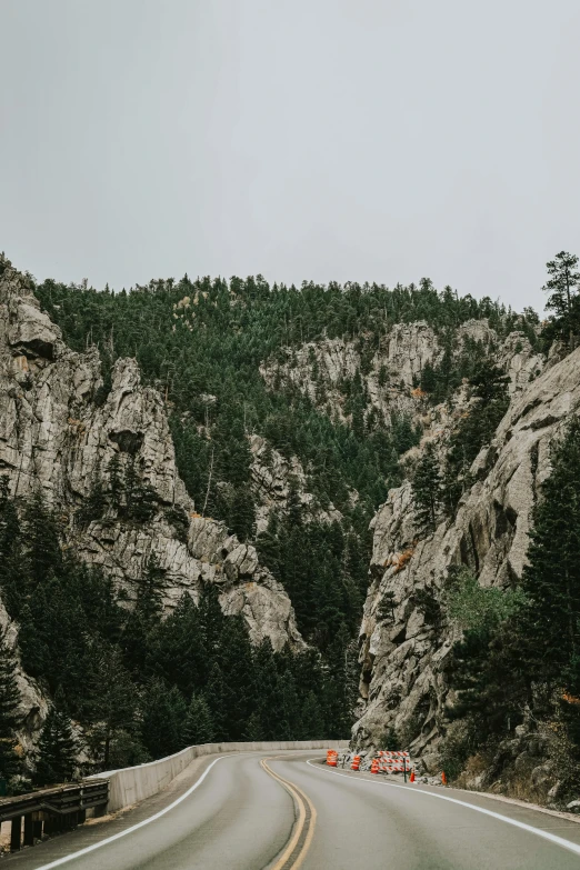 cars driving down a mountain road surrounded by tall cliffs