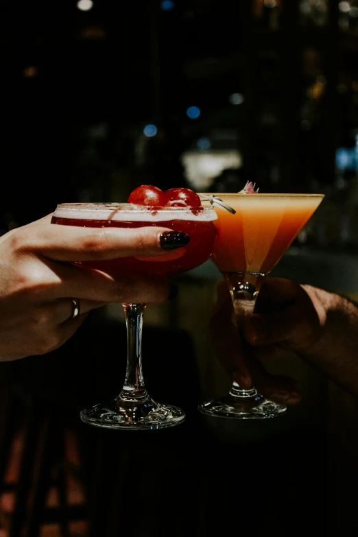 the hands of two people holding up glasses with drinks