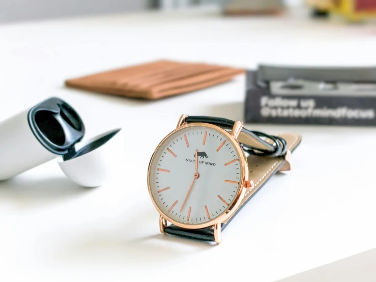 a watch on a black strap sitting next to a card