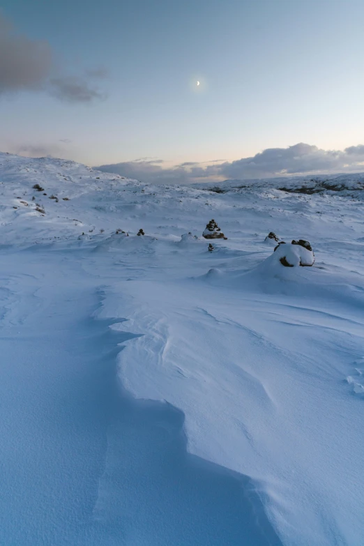 snow covered hill with two people walking on the top