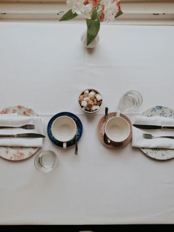 a small cup sitting on a table with plates and glasses