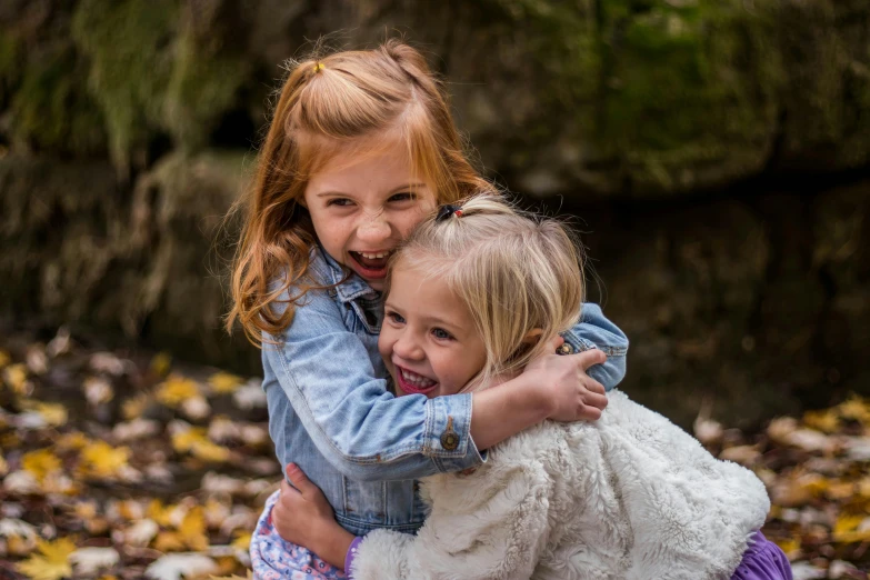 two girls are sitting on the ground playing