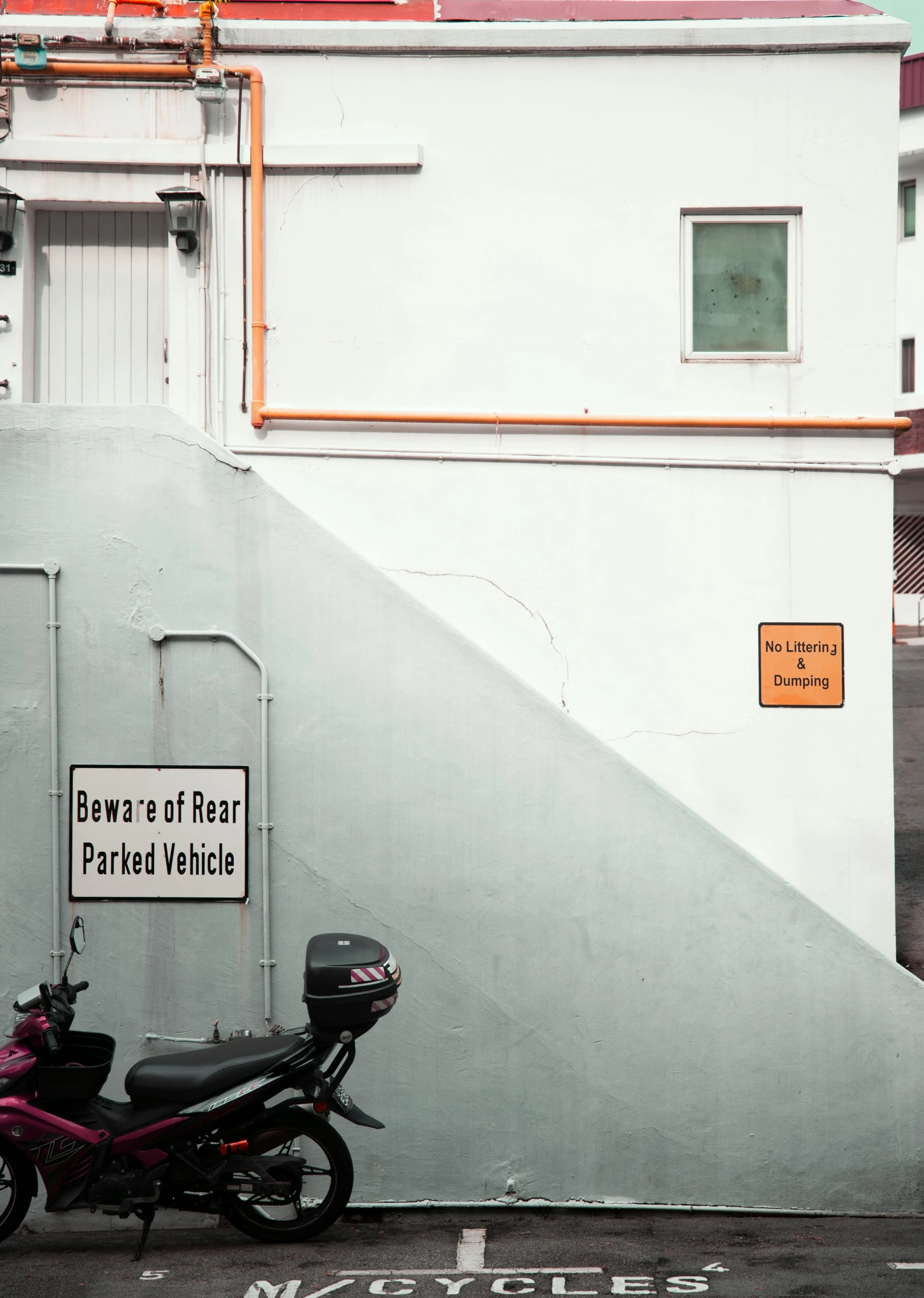 the motorcycle parked next to the building has two street signs on it