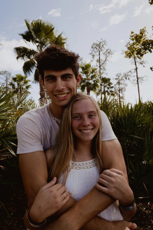 a man and woman sitting next to each other in front of trees