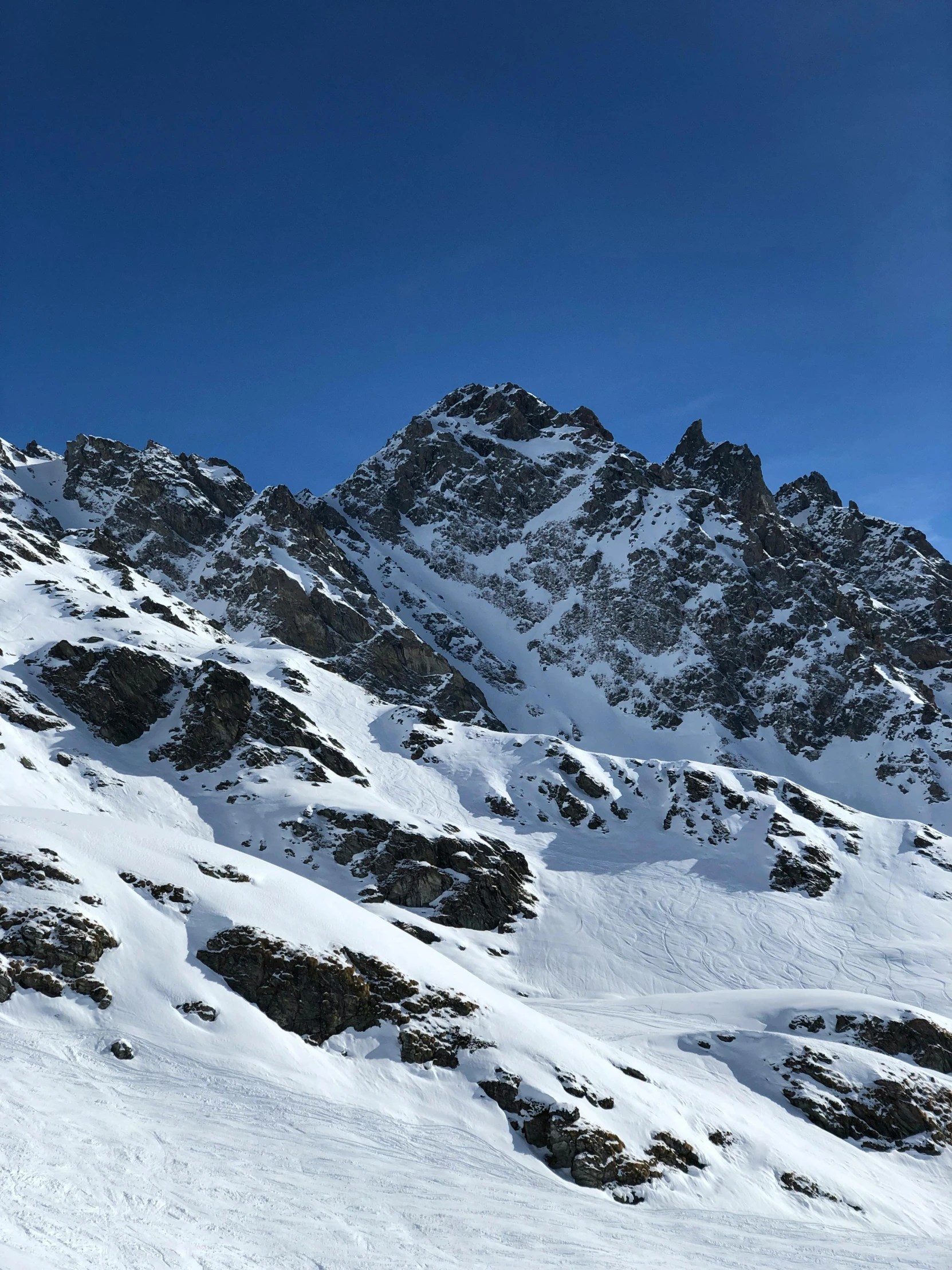 a man in ski gear stands in front of snowy mountains