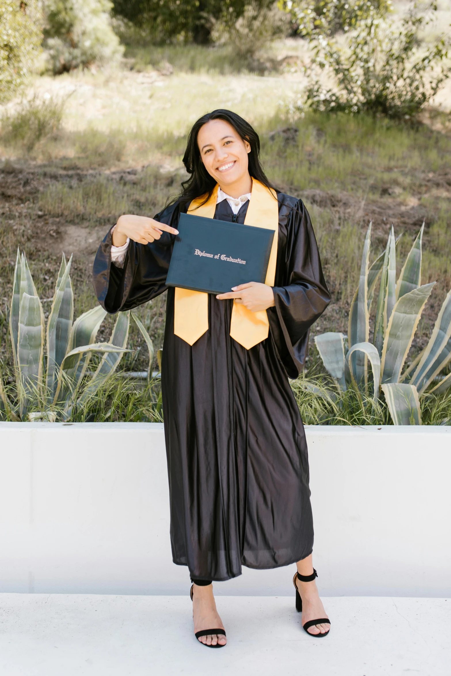 woman in graduation gown holding up her diploma