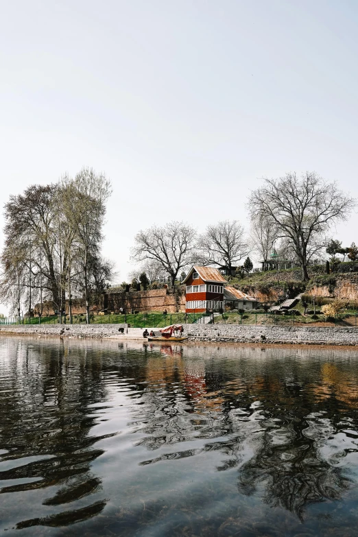 a red house near some water next to a lot of trees