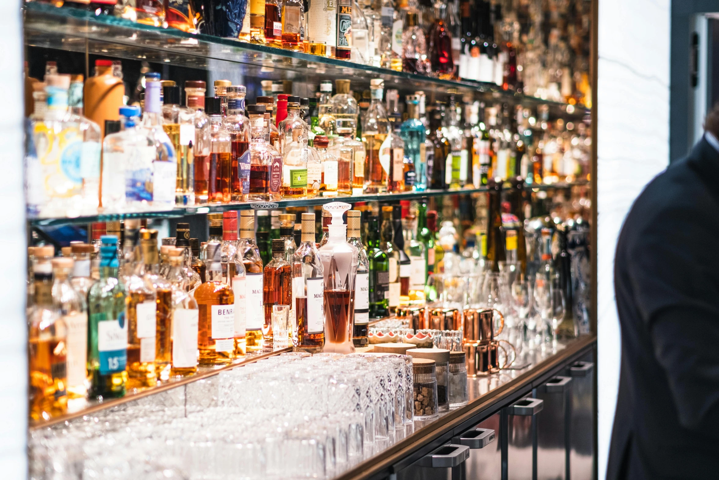 a glass shelf holding bottles with liquor on it