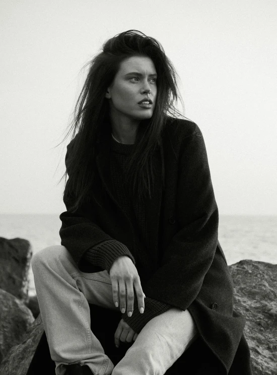 a person sitting on rocks by the ocean