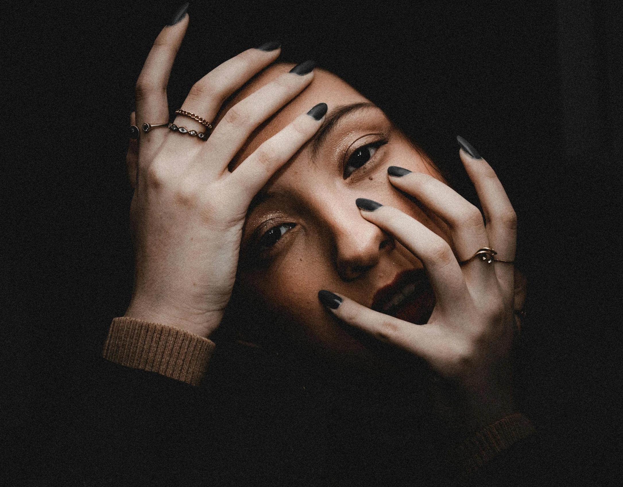 a woman's hands and a ring on her face