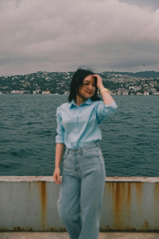 a girl is standing near the water taking a picture