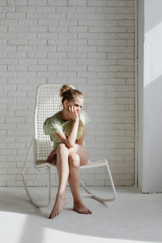 girl sitting in white chair and looking bored