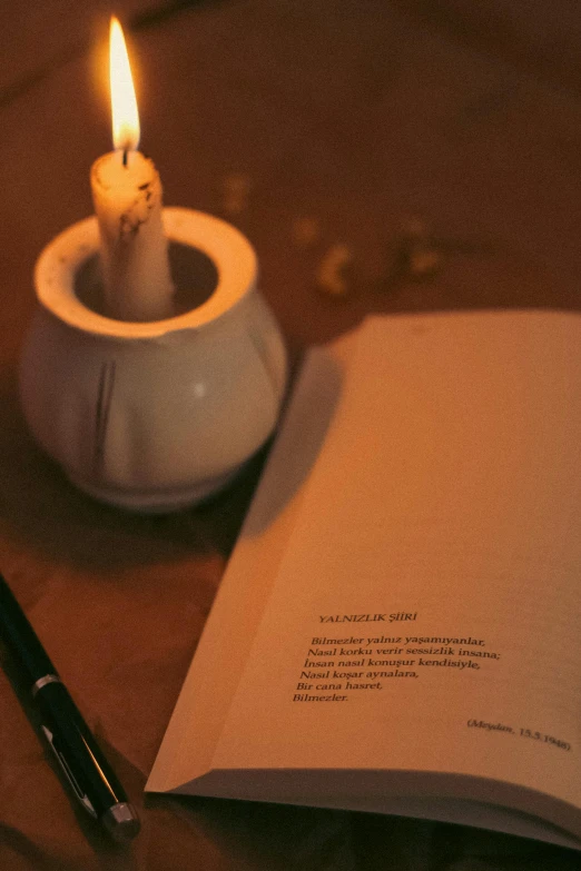 a candle sitting next to a book and pen