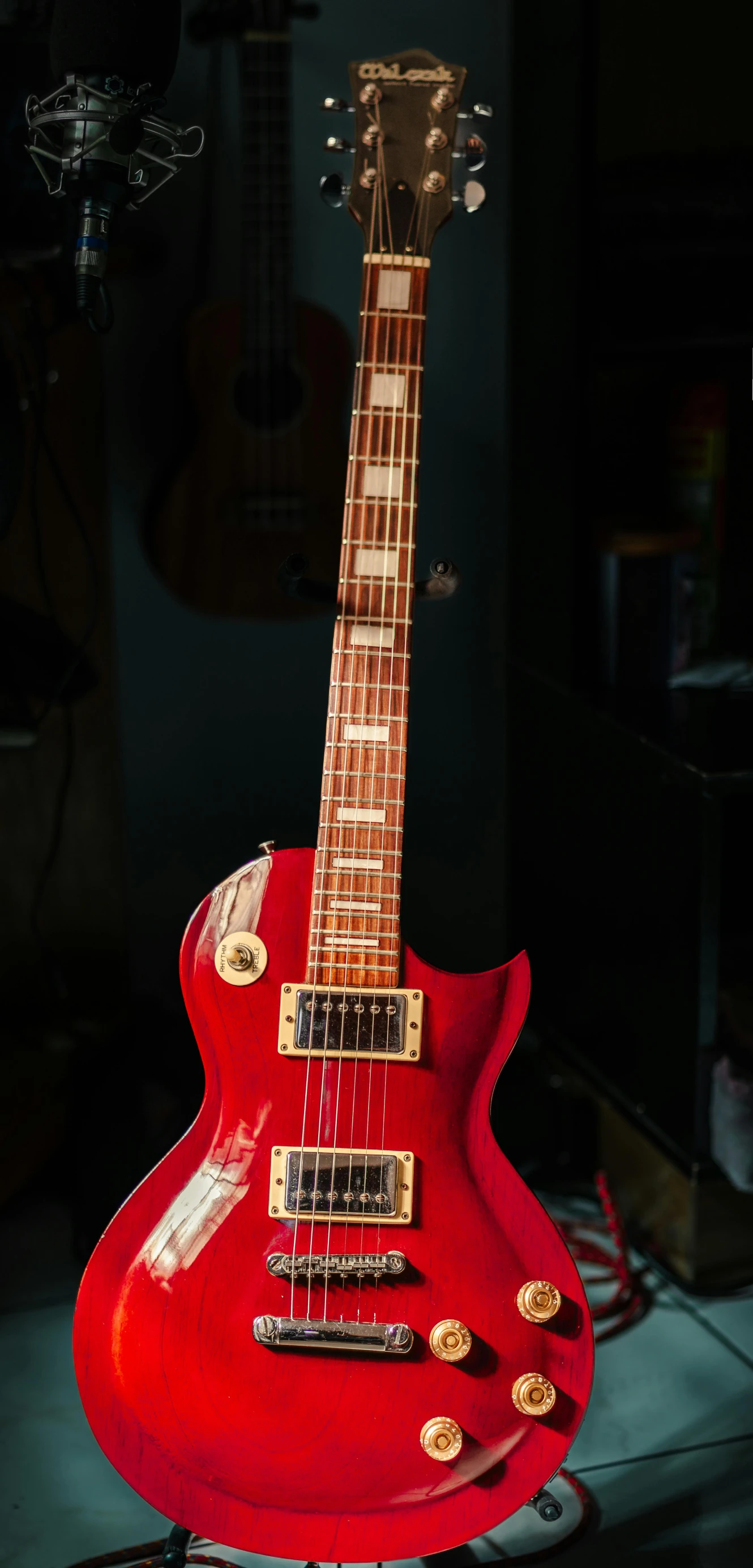 a red guitar sitting on top of a black stand