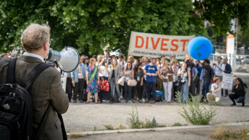 a large crowd watches as a man speaks in front of a crowd