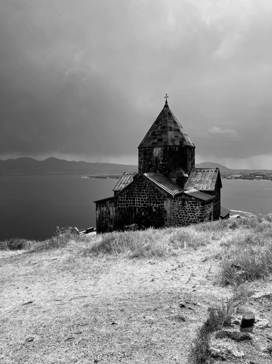 an old church is on a hill with some water in the background