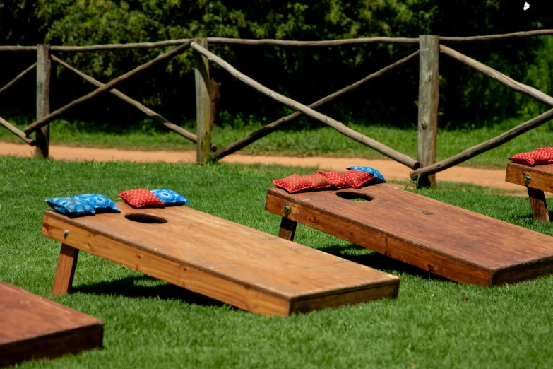 three wooden corn - up boards sitting on top of a grass field