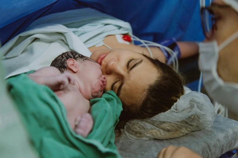 a woman and a baby lie on a hospital bed