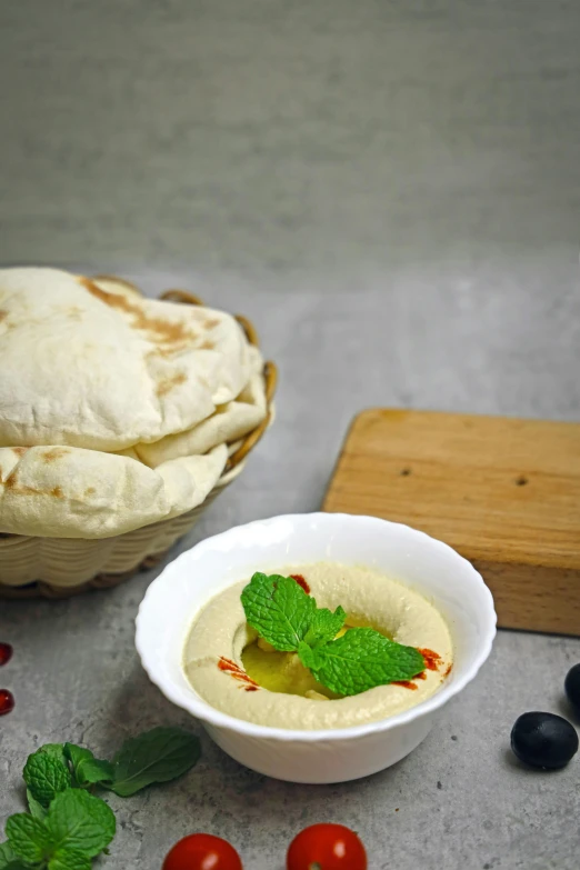 the bowl of hummus is next to some pita bread