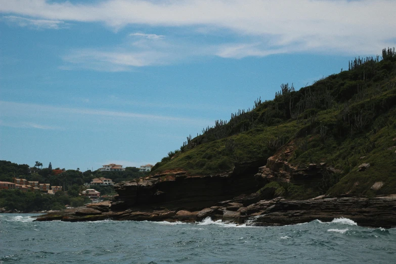 water with rocky cliff behind it and a village in the background