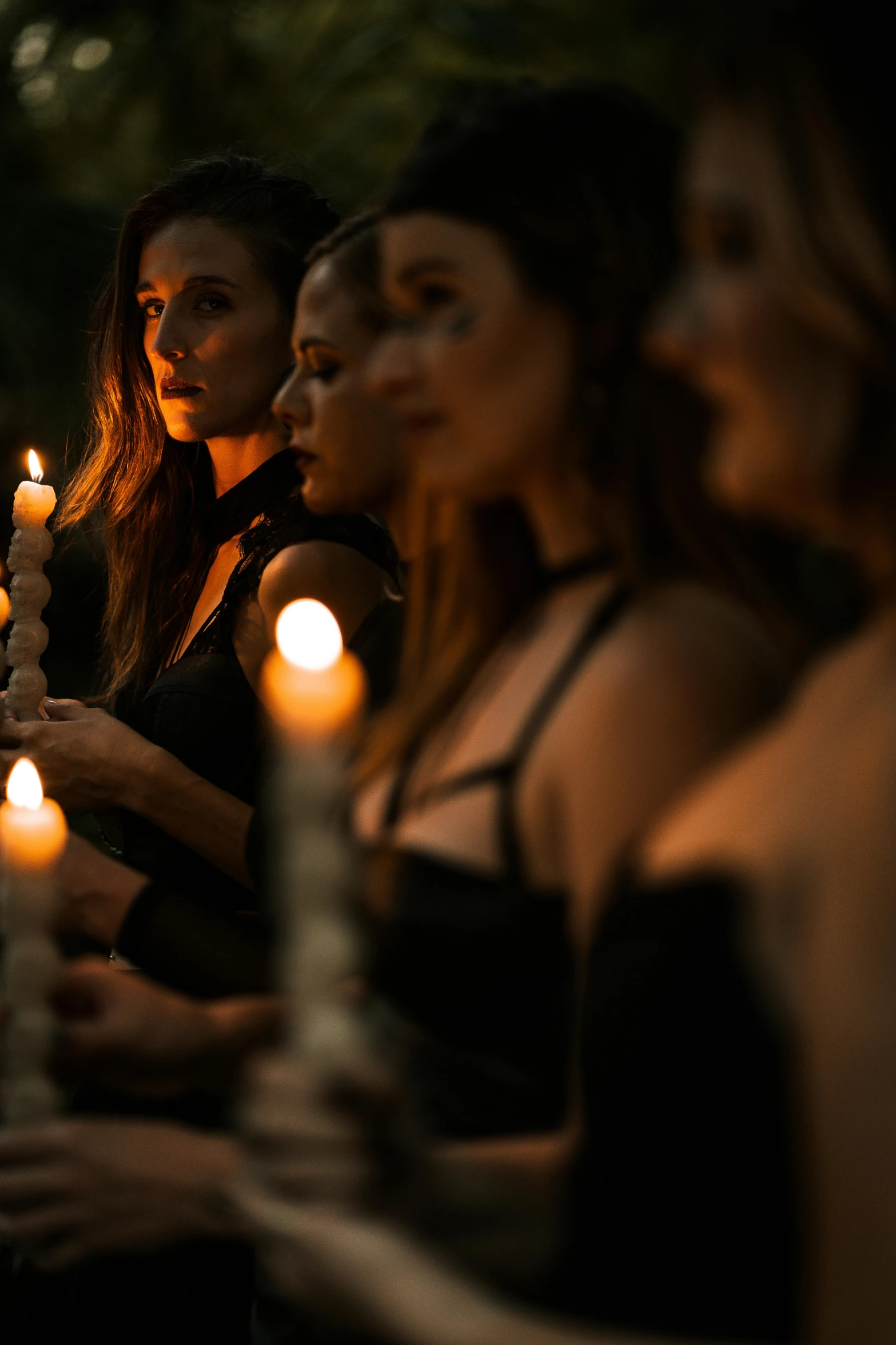 four girls lit candles at a ceremony, one looking up