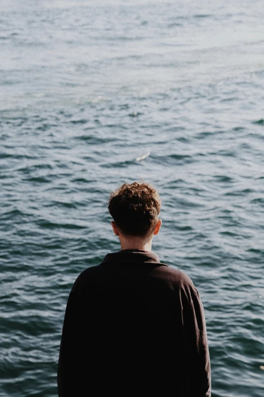 a person looking out over water with a bird flying in the sky