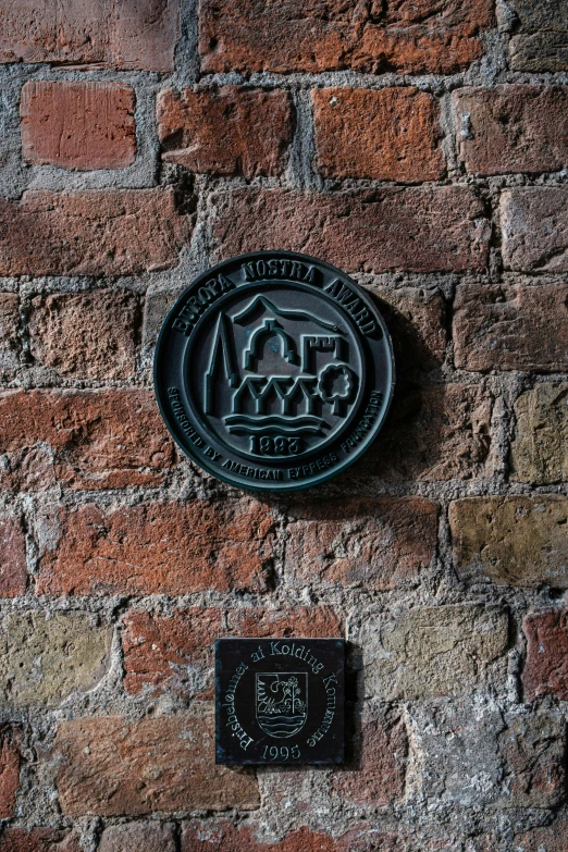 a metal plaque is mounted to the side of a brick wall