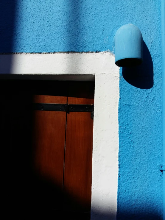 an object with a wooden door is hanging on a blue wall