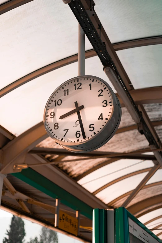 a clock hangs above the ceiling of a covered station