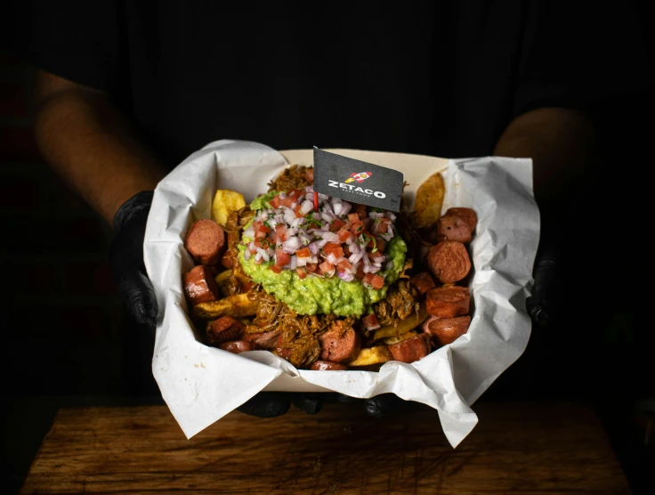 a person holding a  dog with guacamole and tomatoes