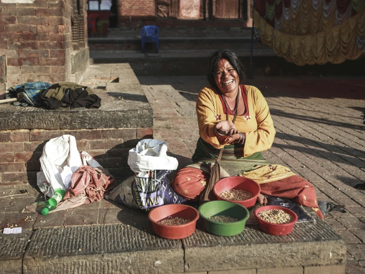 a woman sitting on the steps with several bowls and baskets around her