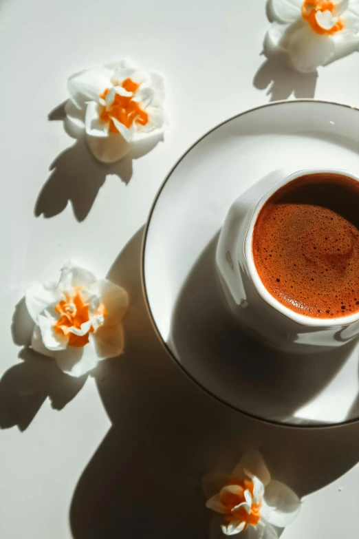 a coffee cup is on the table with orange and white flowers