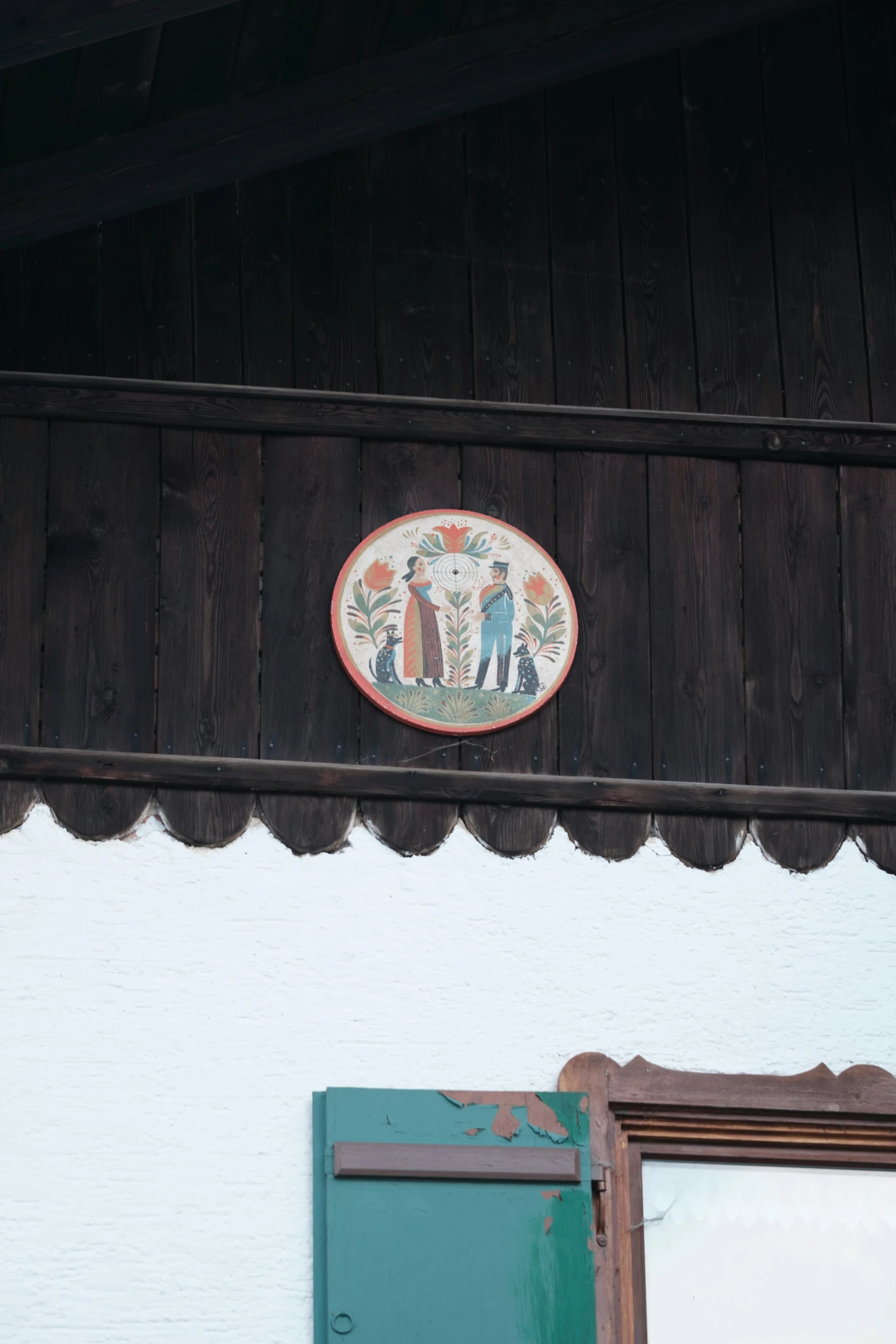 a decorative tile above a window on the side of a house