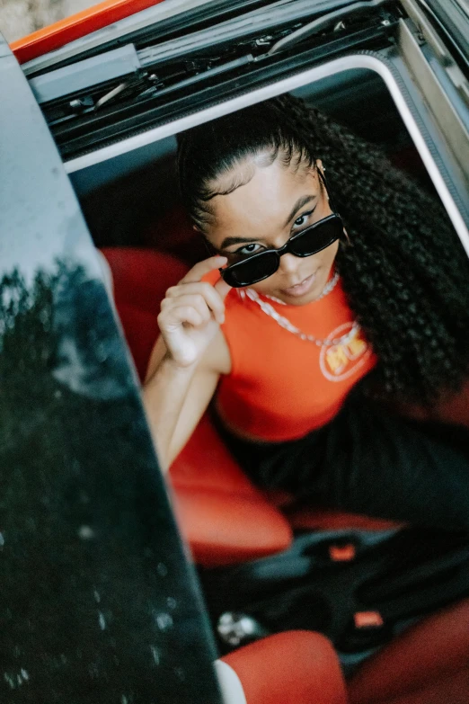 a woman with sunglasses sits inside an open trunk