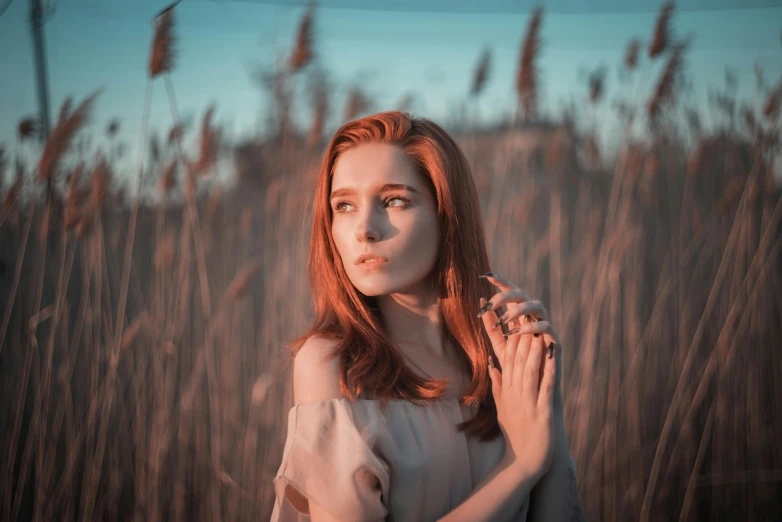 a woman is posing in tall grass on a sunny day