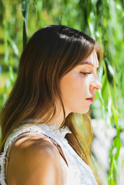 a woman with long hair standing in front of some trees