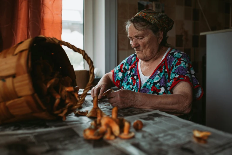 a woman in colorful shirt sitting at a table making soing