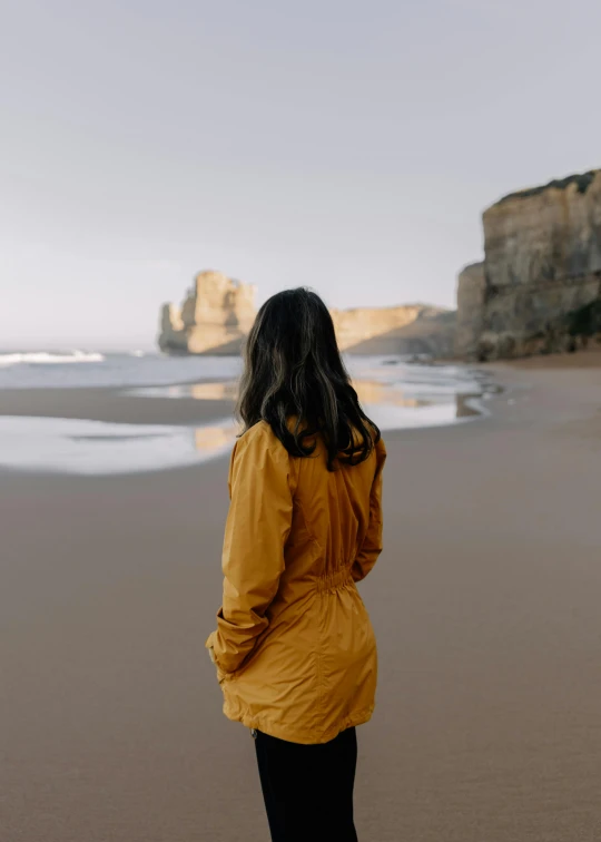 the girl is standing on the beach watching the waves