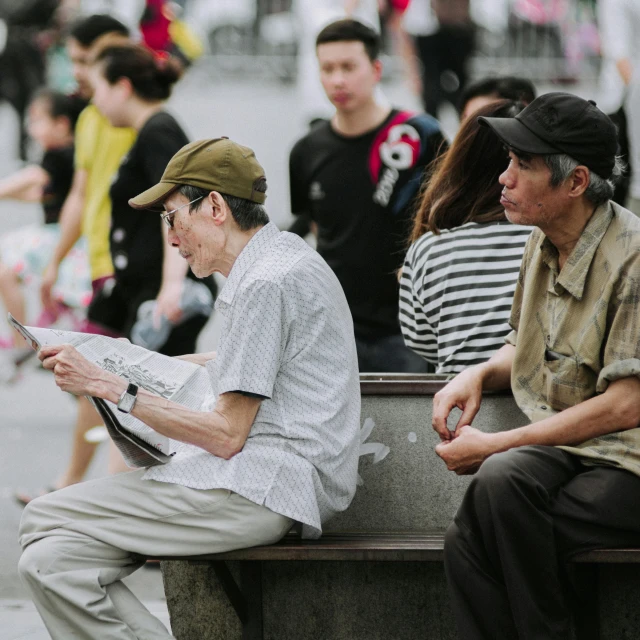 a couple of people sitting on a bench with papers