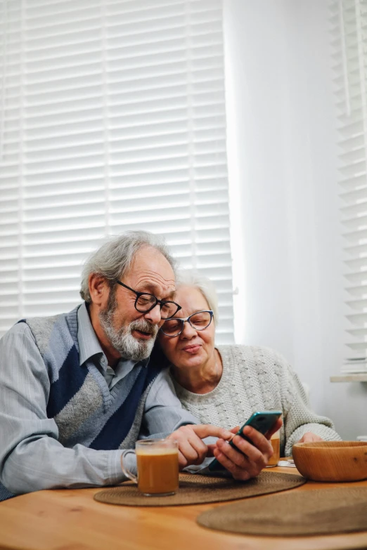 a woman sitting next to an older man holding a cup