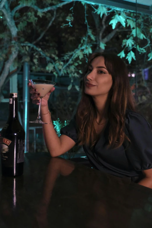 a woman sitting at a bar holding a drink