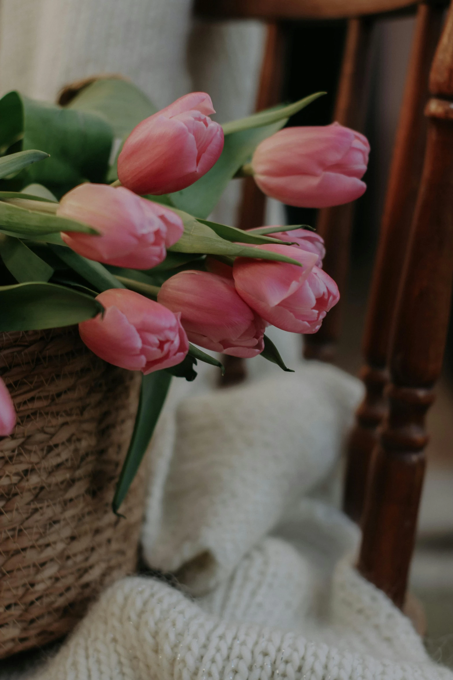 a small basket full of pink flowers on the floor