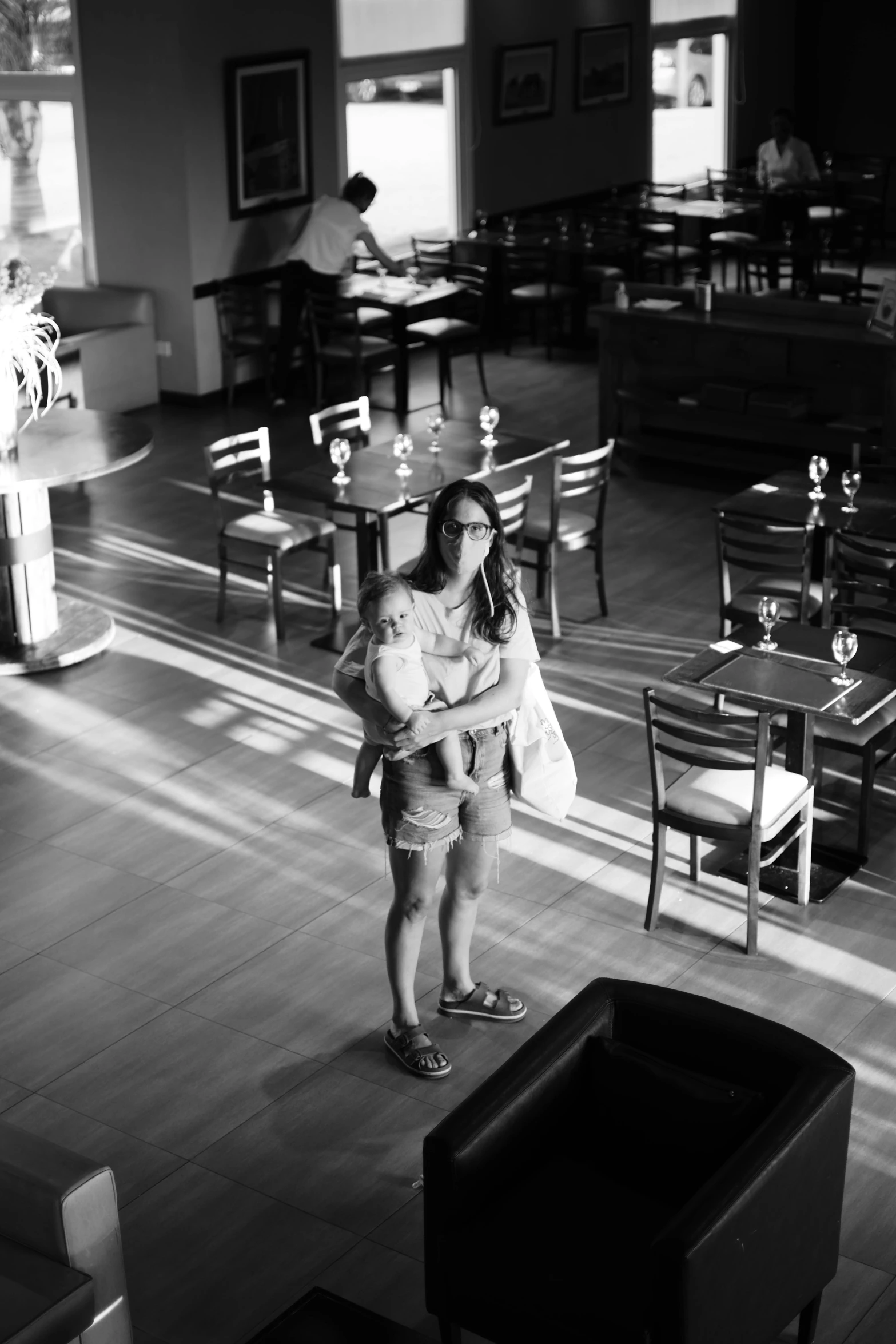 a woman standing in an empty restaurant with the sun lighting her arm