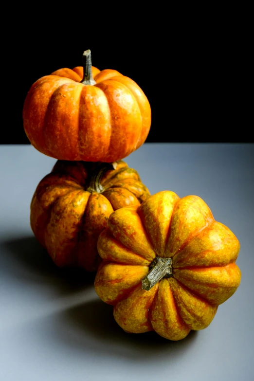 three orange pumpkins sitting next to each other