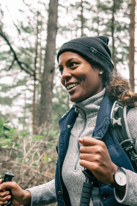 a woman hiking through the woods holding her cell phone