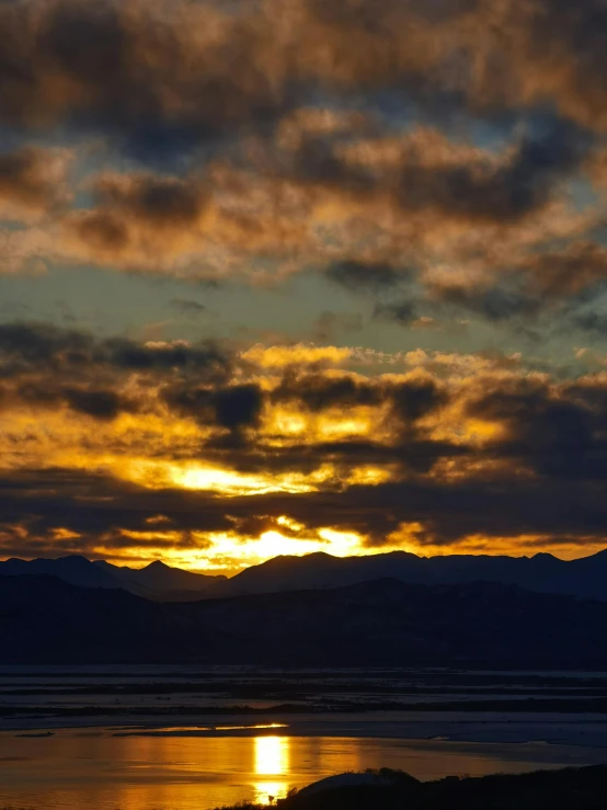 a plane flying through a cloudy sky over mountains