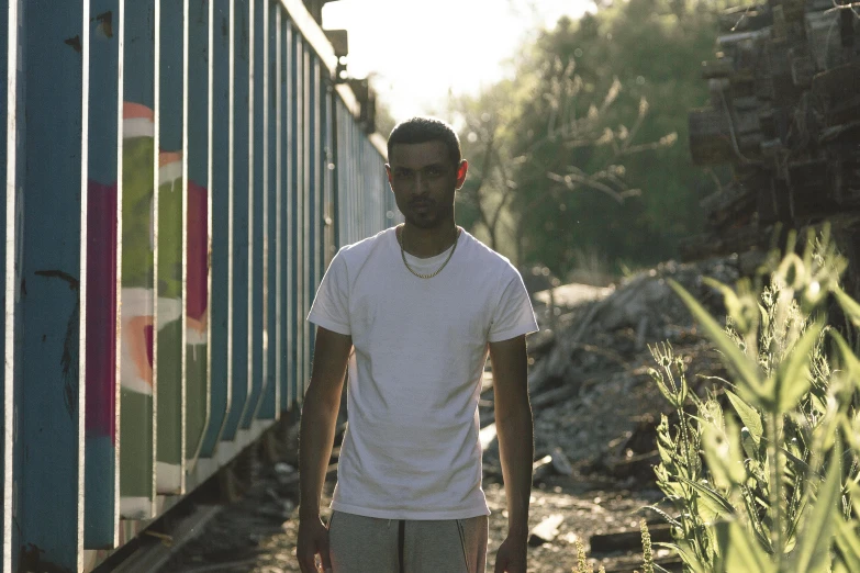 a man walks on railroad tracks in front of a colorful train car