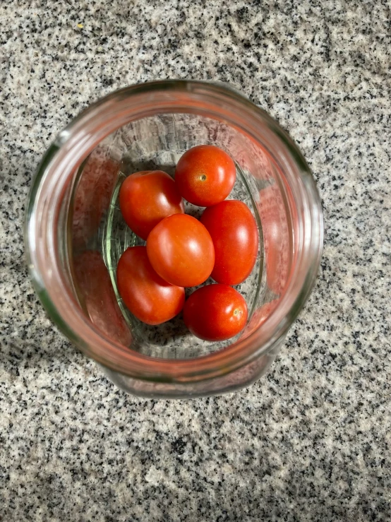 some tomatoes are sitting inside a glass bowl