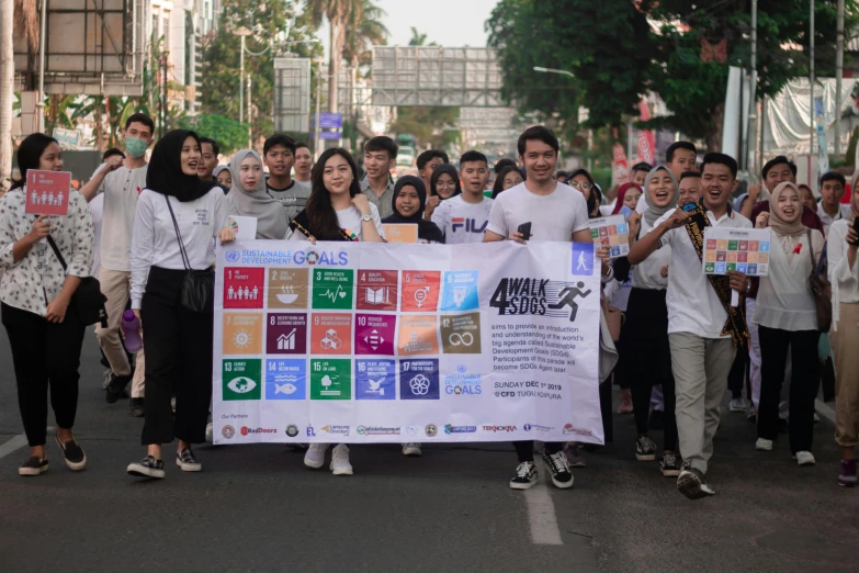 a large group of young people are standing in the street holding up a sign